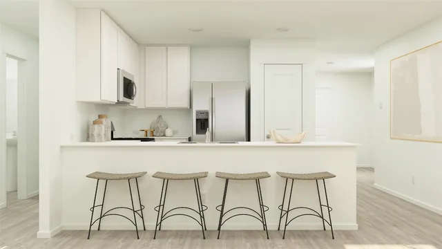 a white kitchen with cabinets a sink and chairs