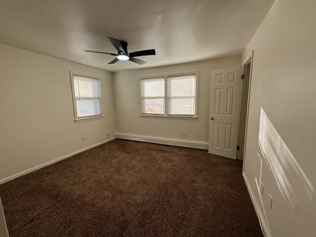 an empty room with windows and fan