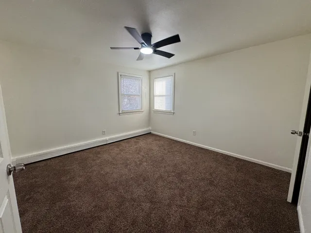 an empty room with a window and a ceiling fan