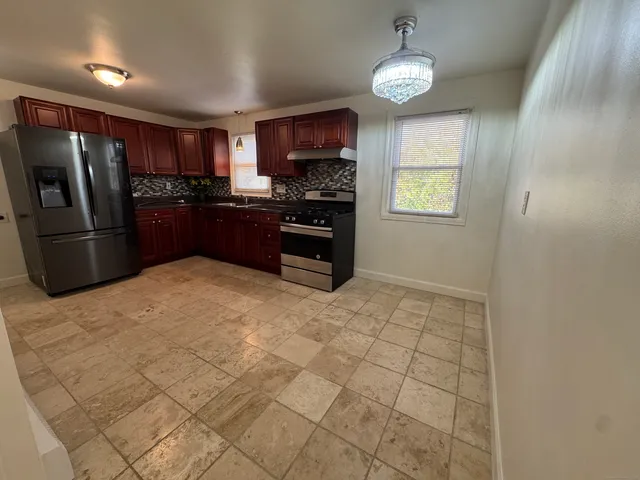 a kitchen with granite countertop a refrigerator and a stove top oven
