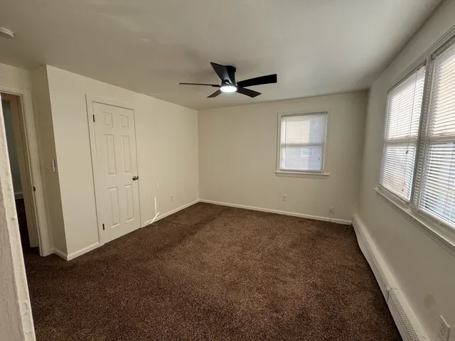 an empty room with windows and fan