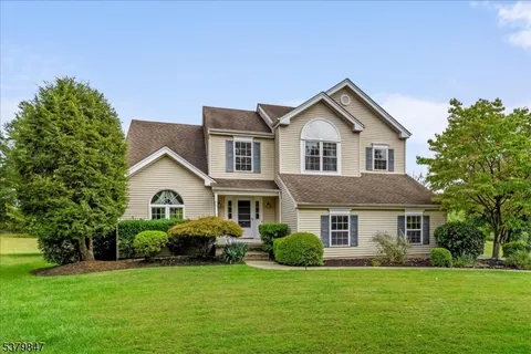 a front view of a house with a garden and trees