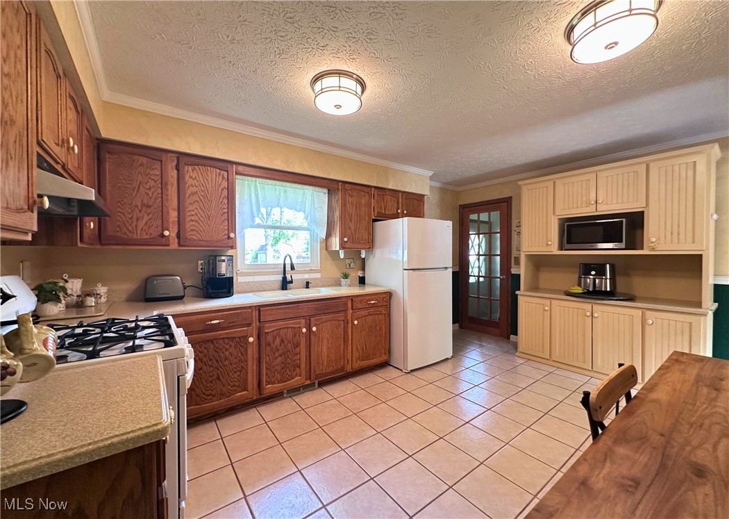 157 Birch Road Painesville, OH 44077 - Photo 11 of 41 Kitchen featuring white appliances, a sink, under cabinet range hood, light countertops, and light tile patterned flooring