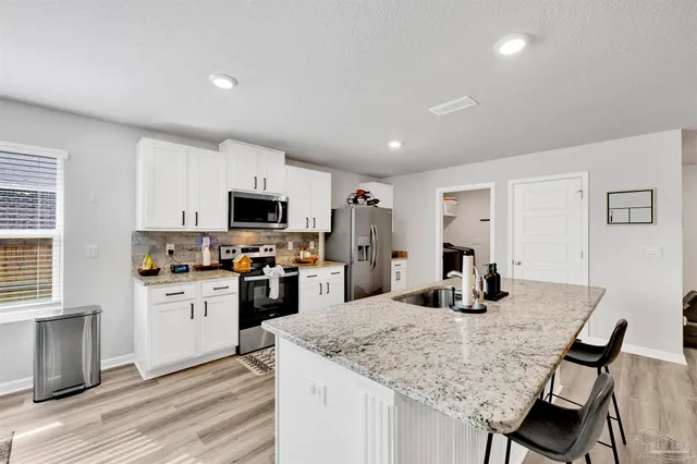 a kitchen with granite countertop a sink counter space and stainless steel appliances