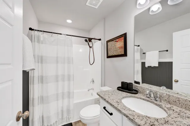 a bathroom with a granite countertop sink toilet a mirror a glass door shower and a mirror