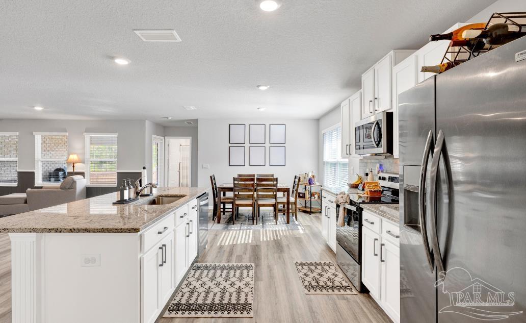 9747 MilleeLoop Loop Pensacola, FL 32526 - Photo 9 of 31 a kitchen with stainless steel appliances granite countertop a refrigerator a sink dishwasher a dining table and chairs with wooden floor