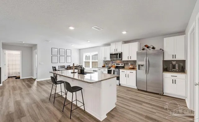 a kitchen with refrigerator and chairs