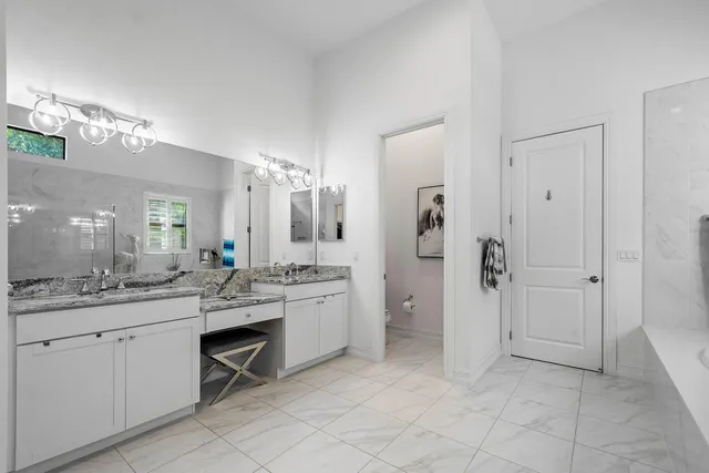 a large bathroom with a granite countertop sink a toilet a mirror and shower