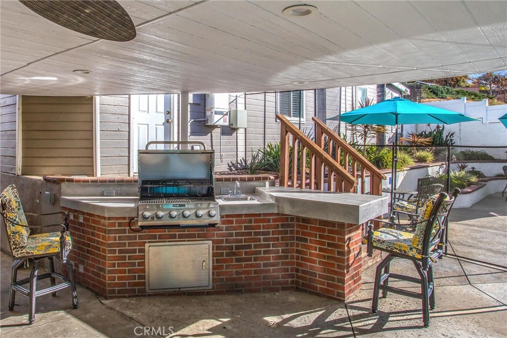 31607 Florida Street Redlands, CA 92373 - Photo 32 of 65 a kitchen with stainless steel appliances kitchen island granite countertop a stove a refrigerator a dining table and chairs with the red umbrella