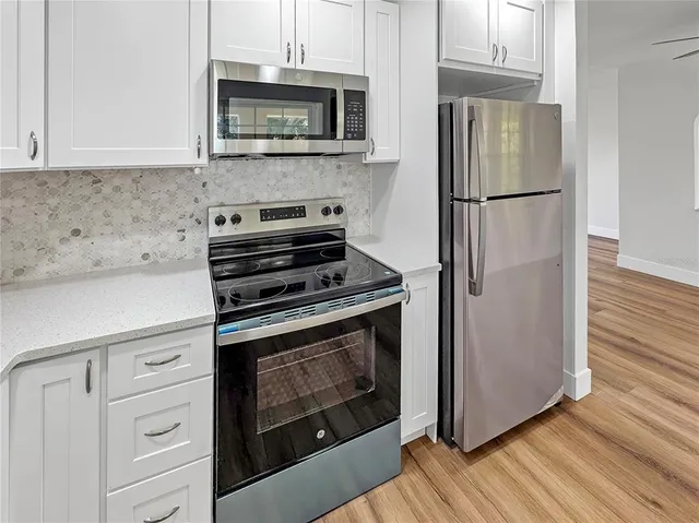 a kitchen with cabinets stainless steel appliances and wooden floor