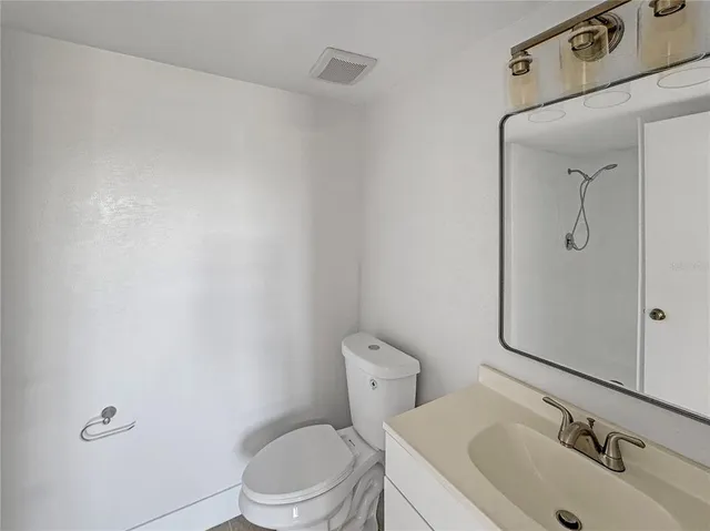 a bathroom with a toilet sink vanity and mirror