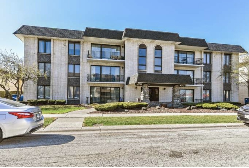 4711 West 106th Street, Unit 2B Oak Lawn, IL 60453 - Photo 1 of 11 a front view of a residential apartment building with a yard