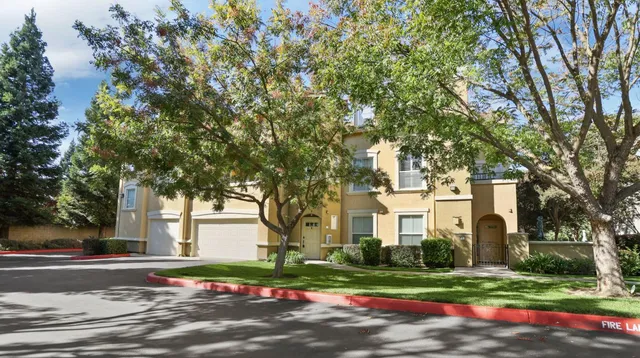 a view of a white house with a yard and large tree