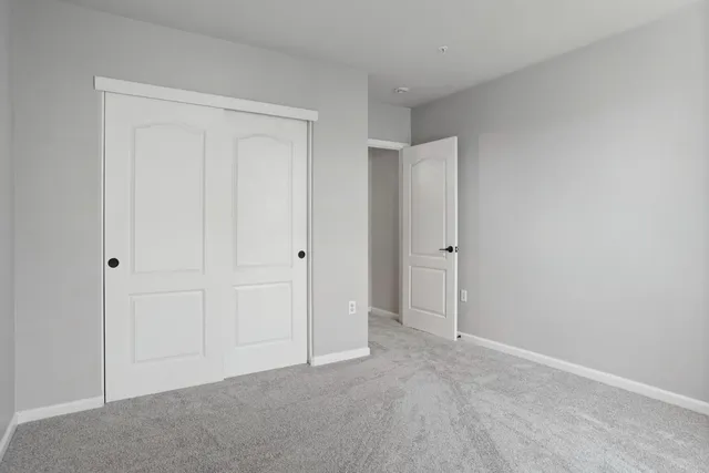an empty room with a ceiling fan and carpet