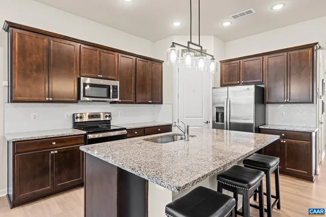 a kitchen with granite countertop kitchen island a sink cabinets and stainless steel appliances