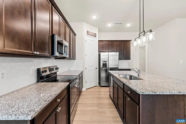 a kitchen with stainless steel appliances granite countertop a kitchen island a stove a refrigerator and a sink