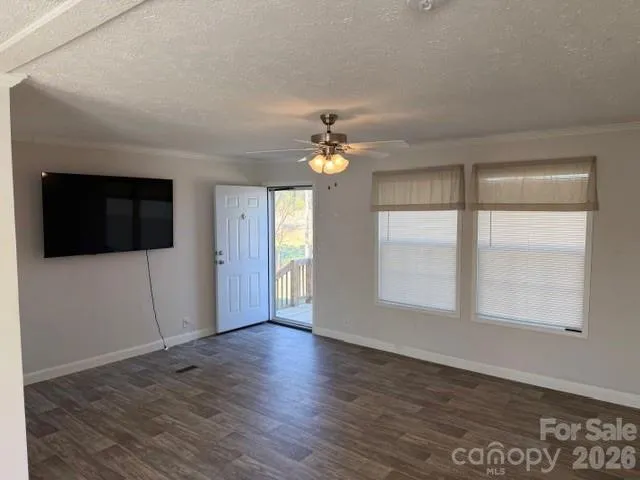 a view of an empty room with a window and wooden floor