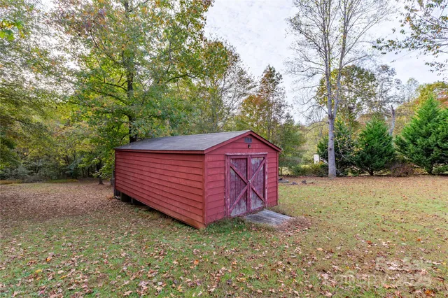 a view of a backyard with large trees and wooden fence