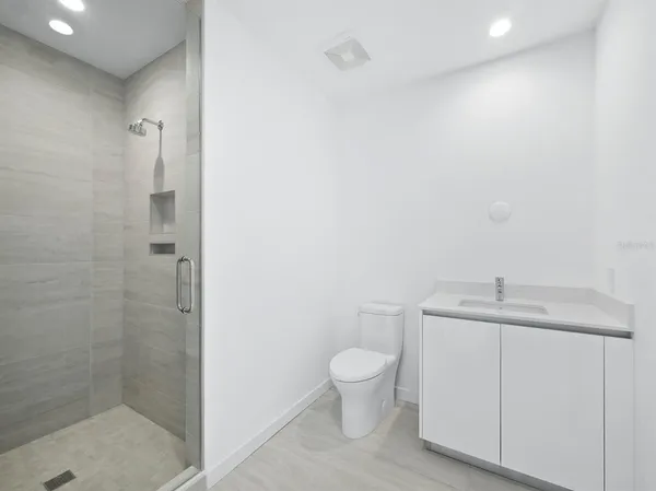 a bathroom with a granite countertop sink a toilet and a shower