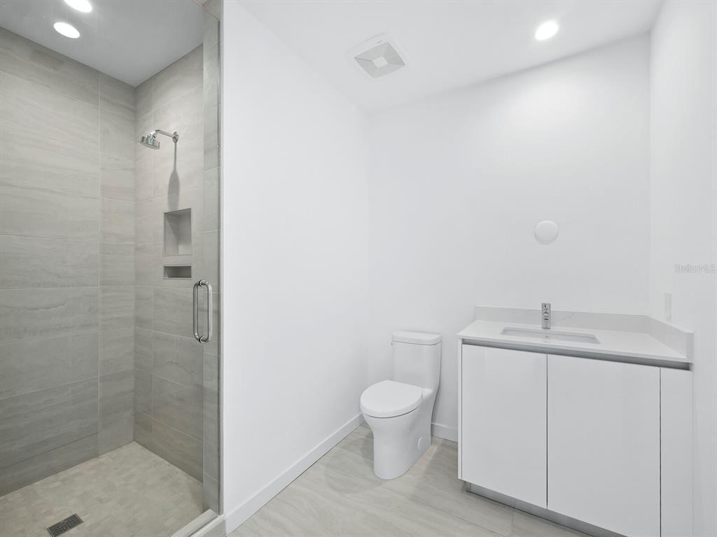 301 Quay Commons, Unit 1409 Sarasota, FL 34236 - Photo 13 of 45 a bathroom with a granite countertop sink a toilet and a shower