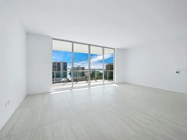 an empty room with floor to ceiling window and an outdoor view