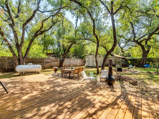 a view of a backyard with table and chairs a fire pit and a large tree