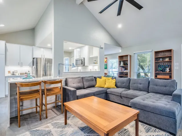 a living room with furniture kitchen view and a wooden floor