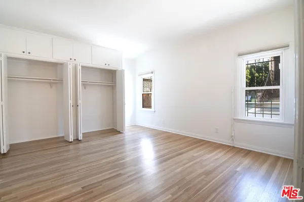 a view of empty room with wooden floor and window