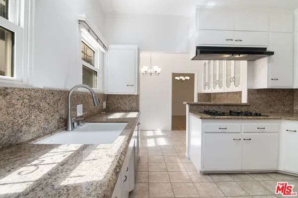 a kitchen with granite countertop a sink a stove and cabinets