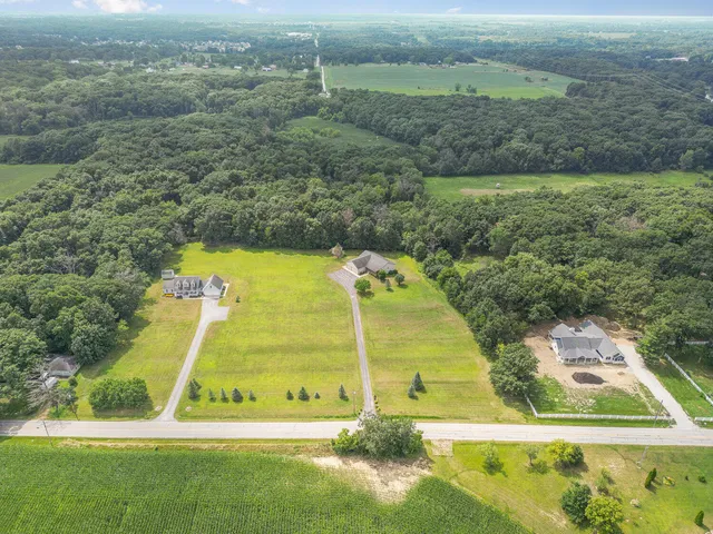 an aerial view of a residential houses with outdoor space and trees