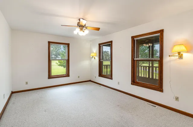 an empty room with windows and chandelier fan
