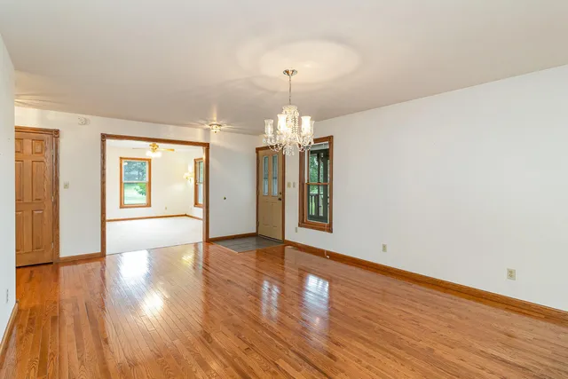 a view of an empty room with window and wooden floor