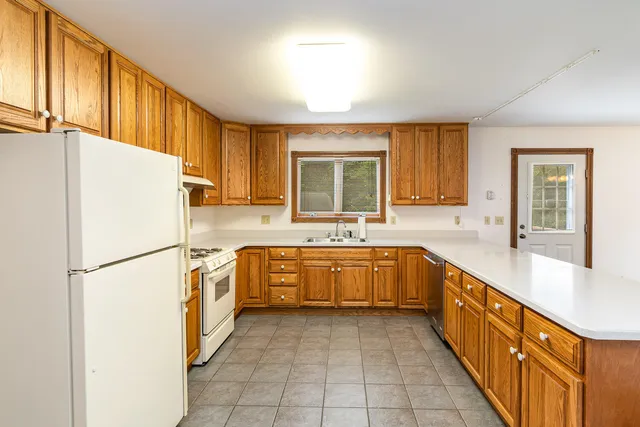 a kitchen with granite countertop a refrigerator a sink dishwasher with a countertop cabinets and wooden floor