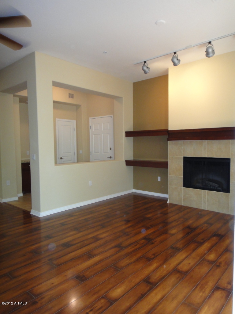 4488 East Thomas Road, Unit 1018 Phoenix, AZ 85018 - Photo 5 of 14 a view of empty room with wooden floor and fireplace