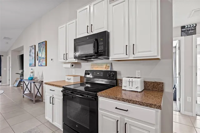 a kitchen with granite countertop a stove a sink and a microwave