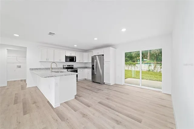a large kitchen with a sink stainless steel appliances and cabinets