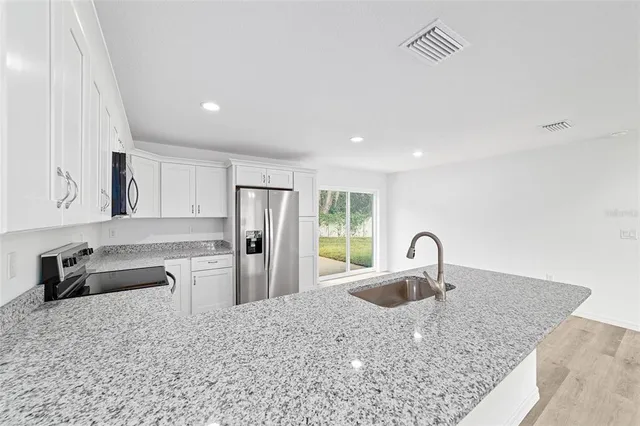 a kitchen with granite countertop white cabinets and a sink