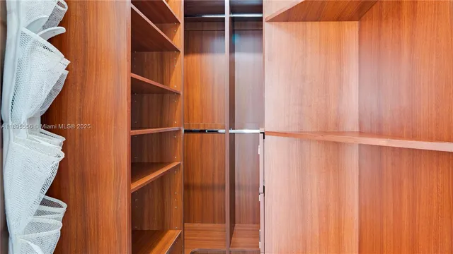 a view of a hallway with wooden floor and a bathroom