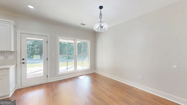 a view of a kitchen with kitchen island stainless steel appliances wooden floor and refrigerator