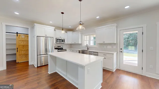 a large kitchen with kitchen island a large counter space a sink appliances and cabinets