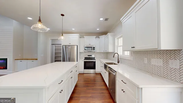 a kitchen with stainless steel appliances granite countertop white cabinets a stove a sink and a microwave