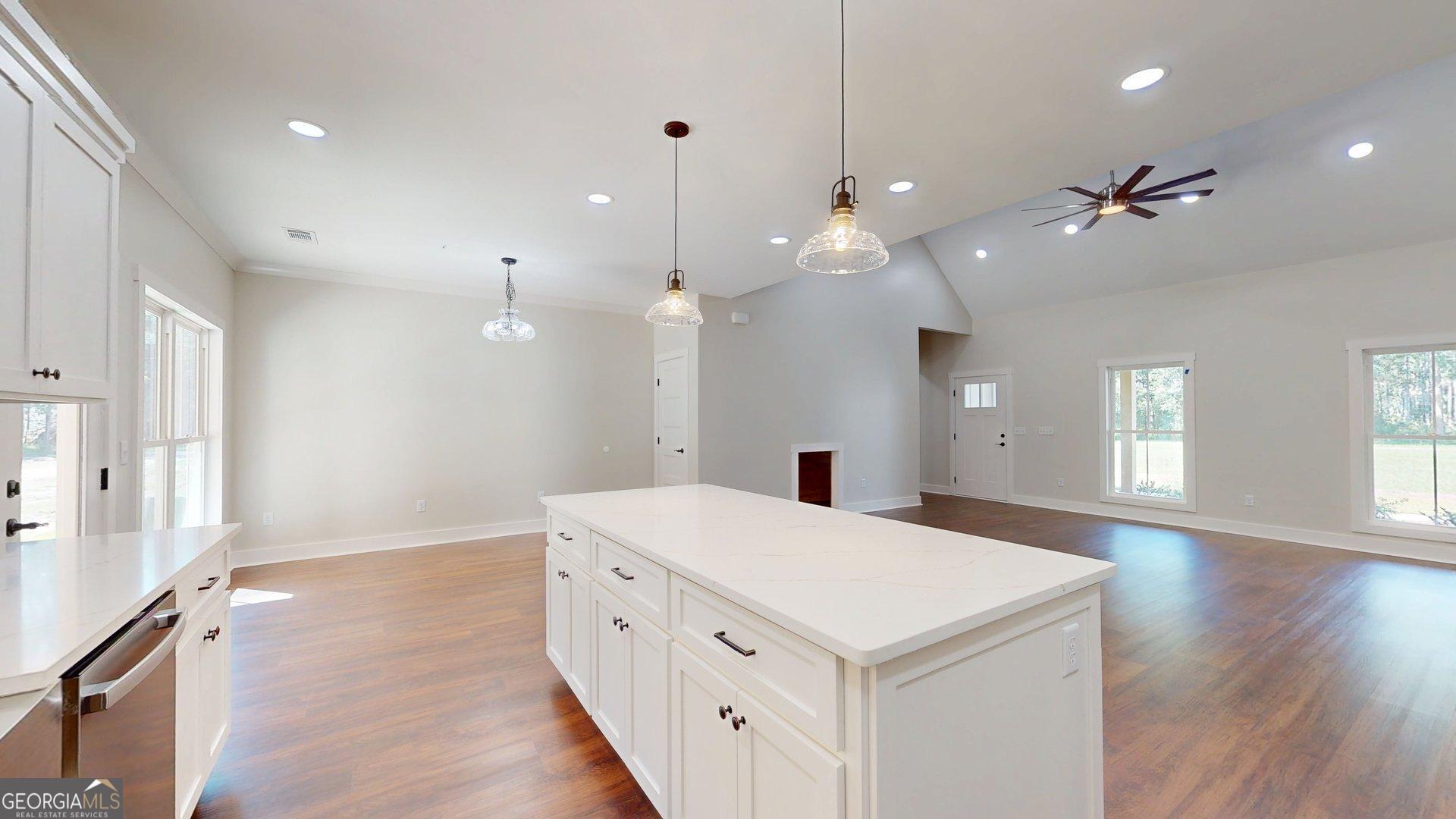 53 Jericho Lane Brooklet, GA 30415 - Photo 19 of 54 a large white kitchen with a large island oven a stove white cabinetry and couches with wooden floor