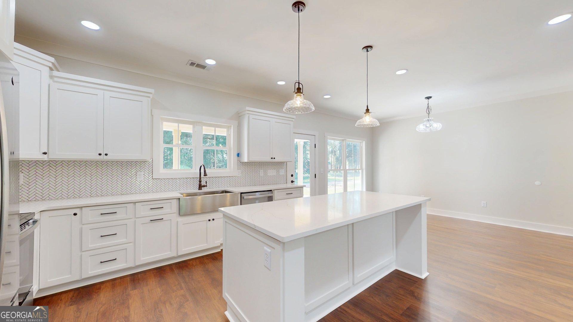 53 Jericho Lane Brooklet, GA 30415 - Photo 20 of 54 a large kitchen with white cabinets a sink a window and wooden floor