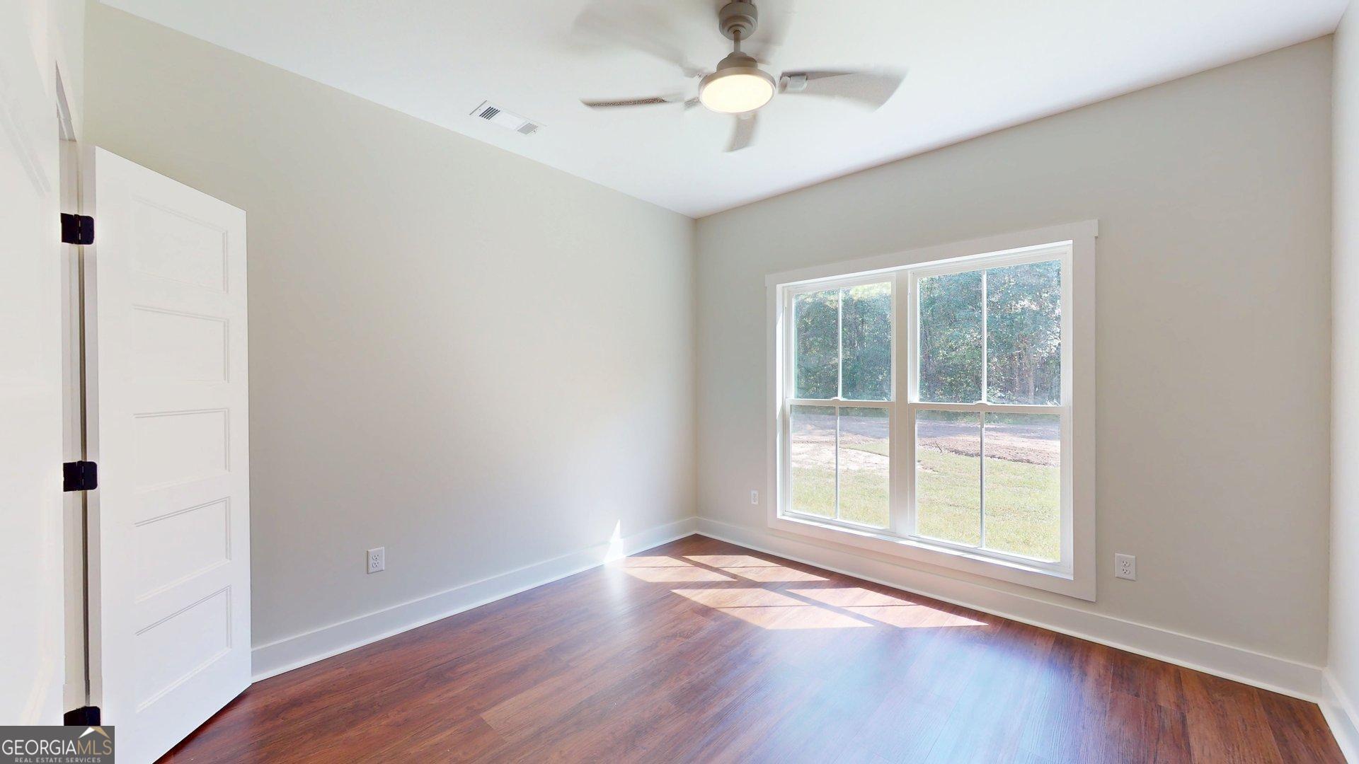 53 Jericho Lane Brooklet, GA 30415 - Photo 32 of 54 an empty room with wooden floor chandelier fan and windows