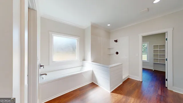 a view of an empty room with a window and wooden floor