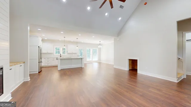 a large kitchen with a center island wooden floor stainless steel appliances and windows