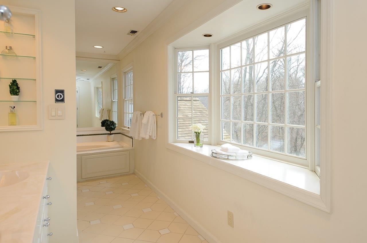 227 Marvin Ridge Road New Canaan, CT 06840 - Photo 19 of 34 a bathroom with a granite countertop sink a large mirror and a bathtub next to a window