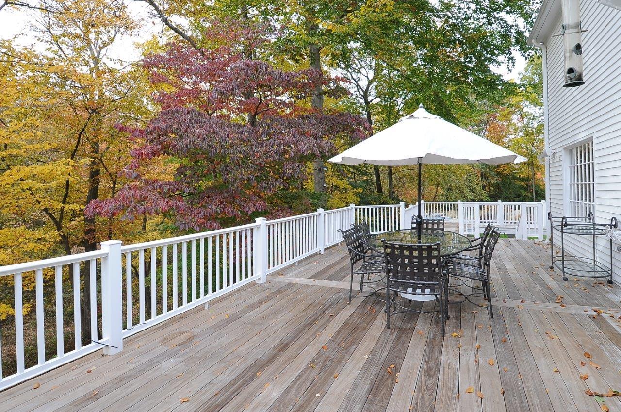 227 Marvin Ridge Road New Canaan, CT 06840 - Photo 9 of 34 a view of a roof deck with table and chairs under an umbrella with wooden floor