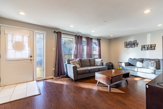 a living room with furniture a large window and wooden floor