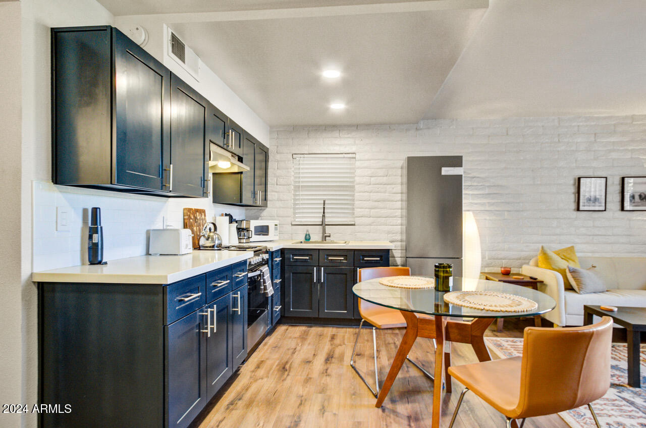 3737 East Turney Avenue, Unit 116 Phoenix, AZ 85018 - Photo 5 of 24 a kitchen with stainless steel appliances granite countertop a table chairs sink and stove